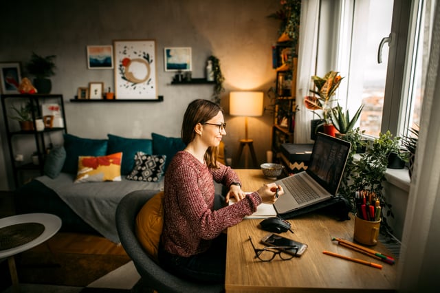 larger image of woman in glasses working on a laptop at home